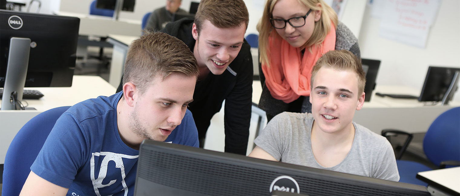 Zu sehen sind männliche und weibliche Jugendliche, die gemeinsam auf einen PC-Bildschirm schauen.