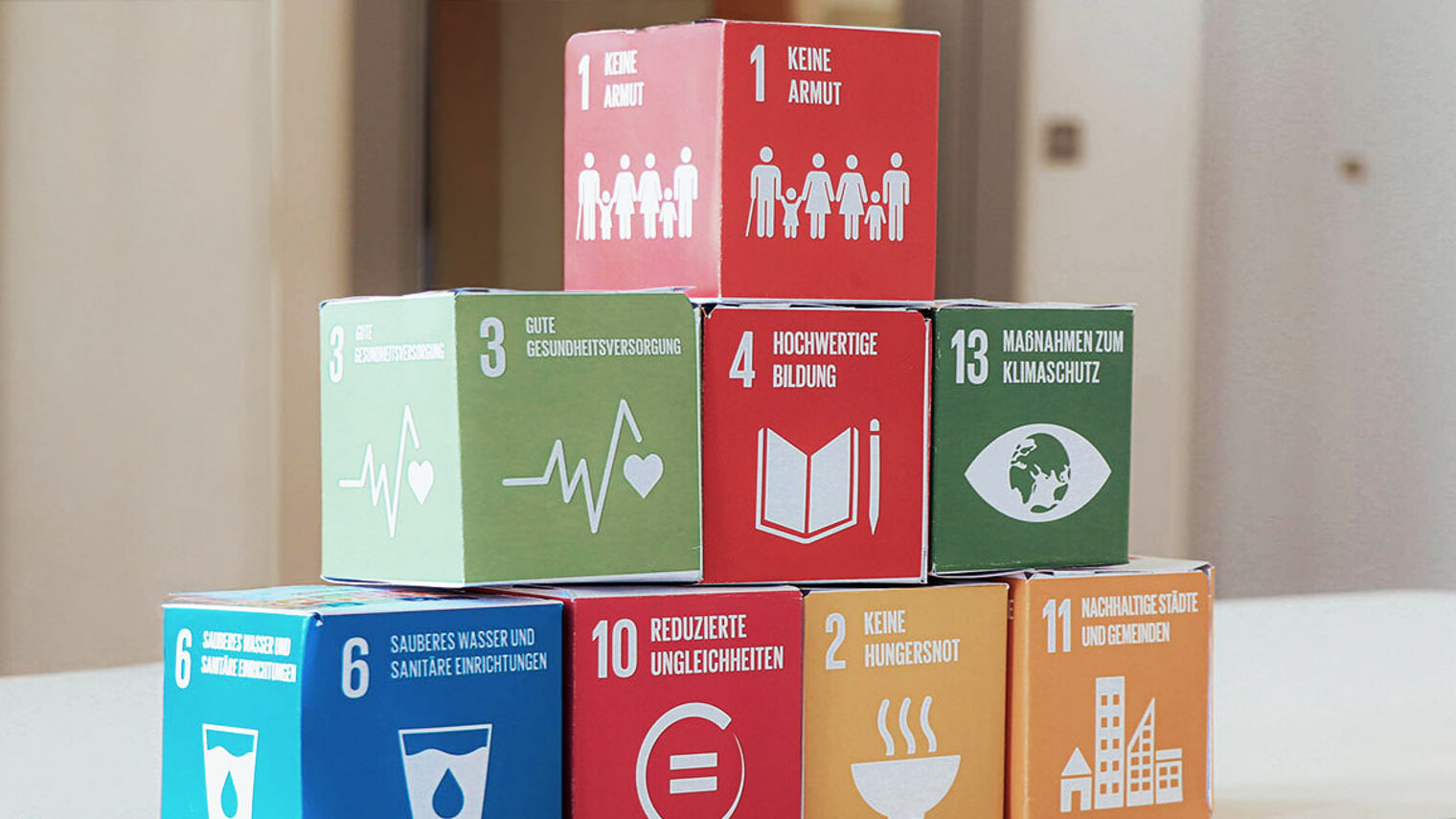 Bausteine der 17 „Sustainable Development Goals“ (SDGs) der UN übereinandergestapelt auf einem Tisch.