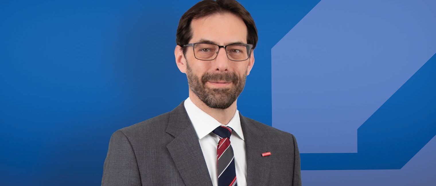 Das Portrait eines Mannes. Er lächelt ein wenig. 
