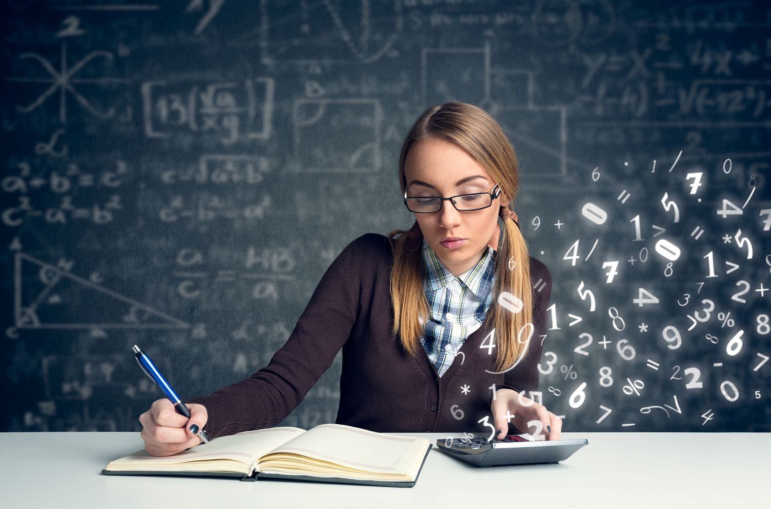 Ein Mädchen sitzt vor einer Tafel mit mathematischen Formeln. Ein Stift ist in ihrer Hand. Vor ihr liegt ein Taschenrechner.