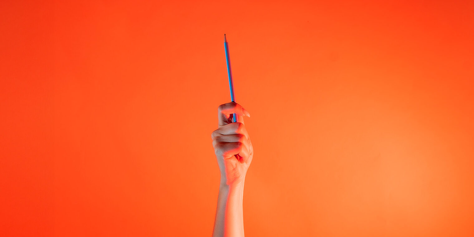 Eine Hand hält einen Stift hoch. 